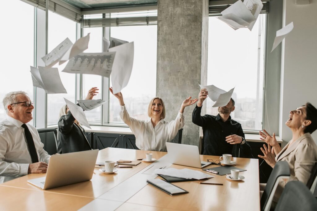 Business team throwing papers in the air in a modern office, celebrating success.